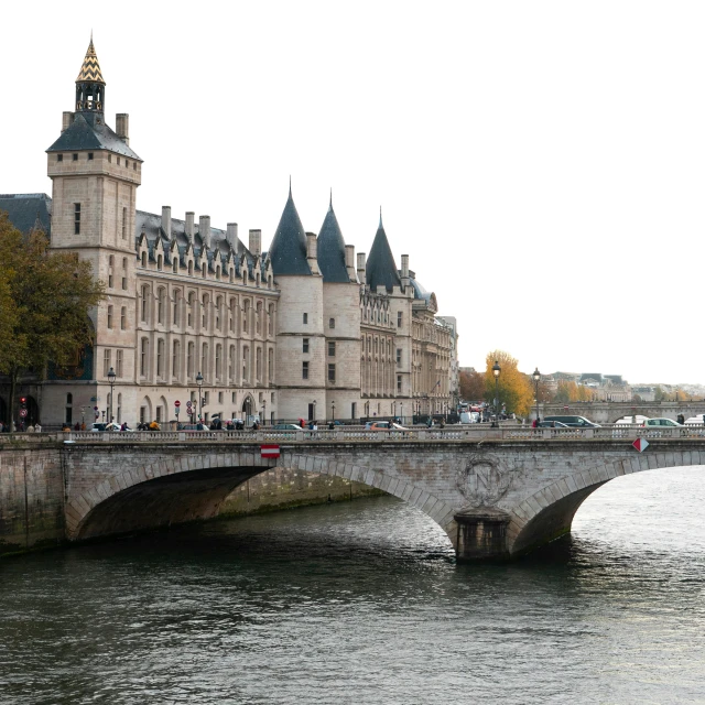 a bridge over a river with a building in the background, pexels contest winner, paris school, tall stone spires, moat, dezeen, cozy