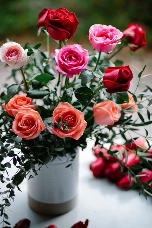 a close up of a vase of flowers on a table, roses and lush fern flowers, multiple colors, roses, no cropping