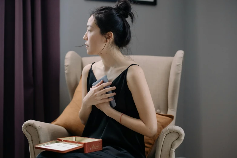 a woman sitting in a chair holding a book, inspired by Qian Xuan, happening, scales on her chest, heart rate, perfume, grey