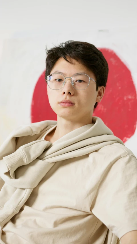 a woman wearing glasses standing in front of a wall, inspired by Joong Keun Lee, song joong - ki portrait, red cloth around his shoulders, ethnicity : japanese, avatar for website