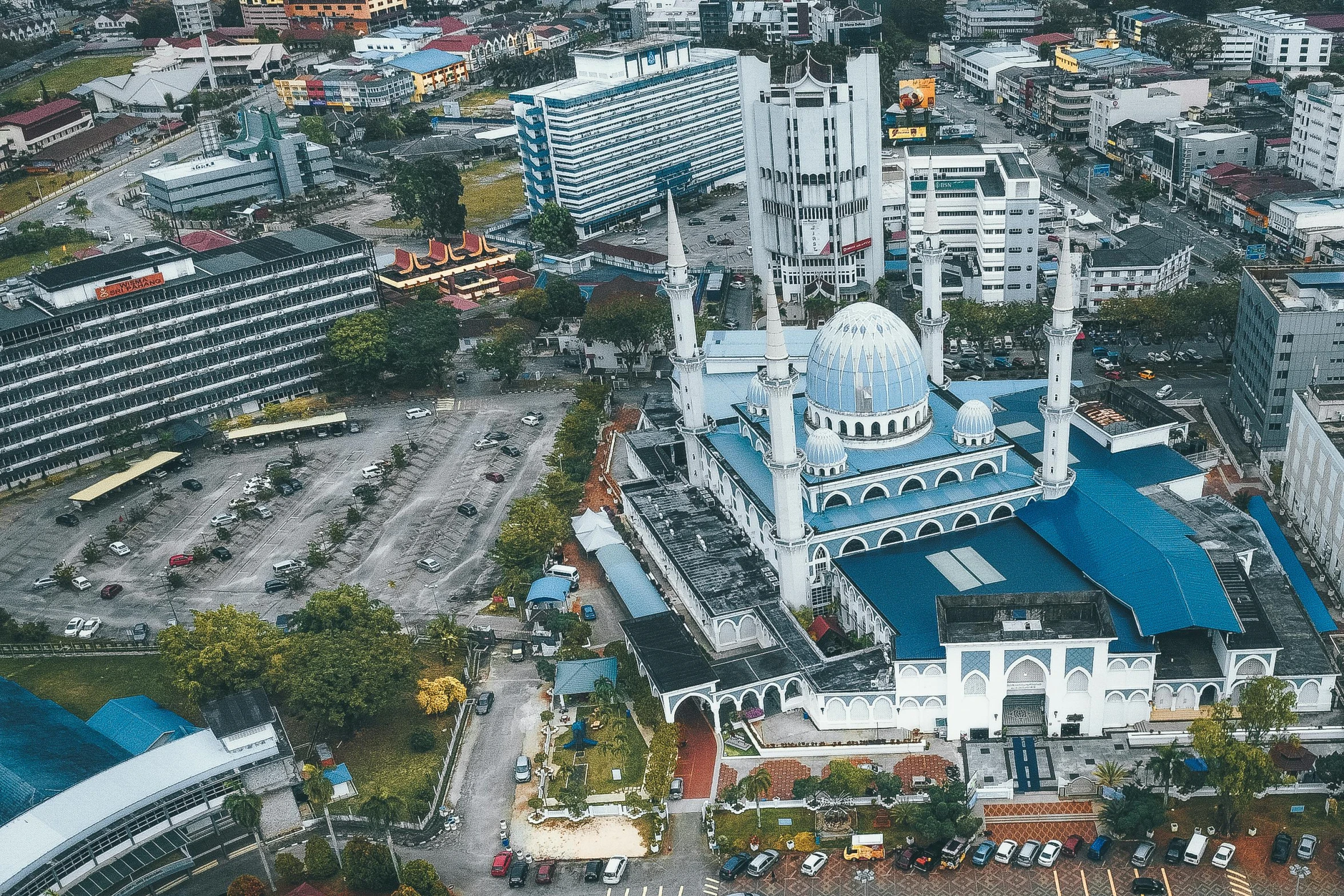 a large white building with a blue roof, a colorized photo, pexels contest winner, hurufiyya, aerial view of a city, malaysian, square, high quality upload