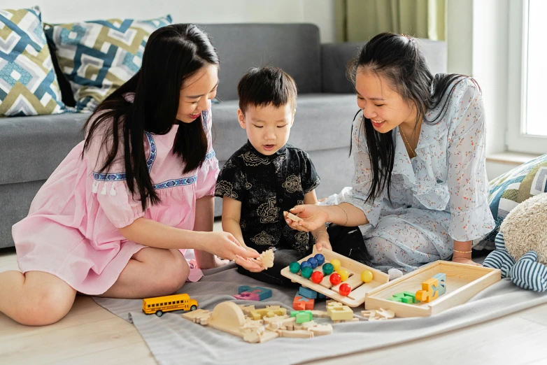 a woman and two children sitting on the floor playing with toys, a jigsaw puzzle, pexels contest winner, ruan jia and brom, on a wooden tray, square, guide