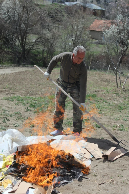 a man that is standing in front of a fire, north korean slasher, using a spade, foil, sweat