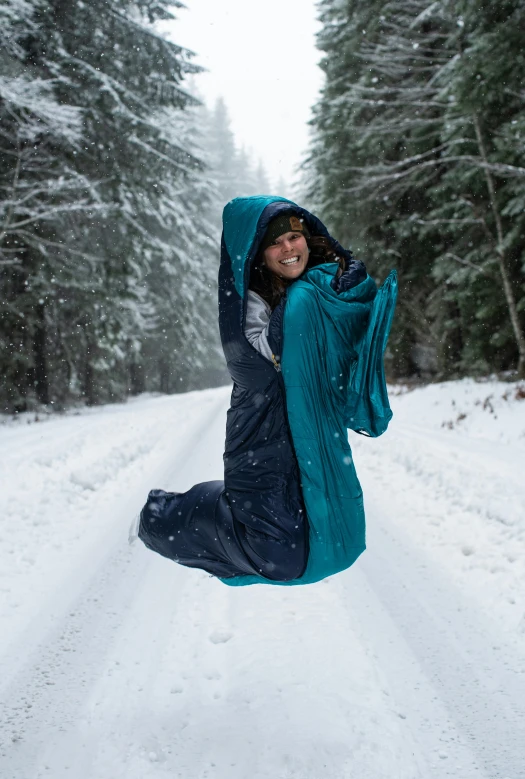 a woman jumping in the air in the snow, by Jessie Algie, sleeping bag, wearing nanotech honeycomb robe, road trip, navy