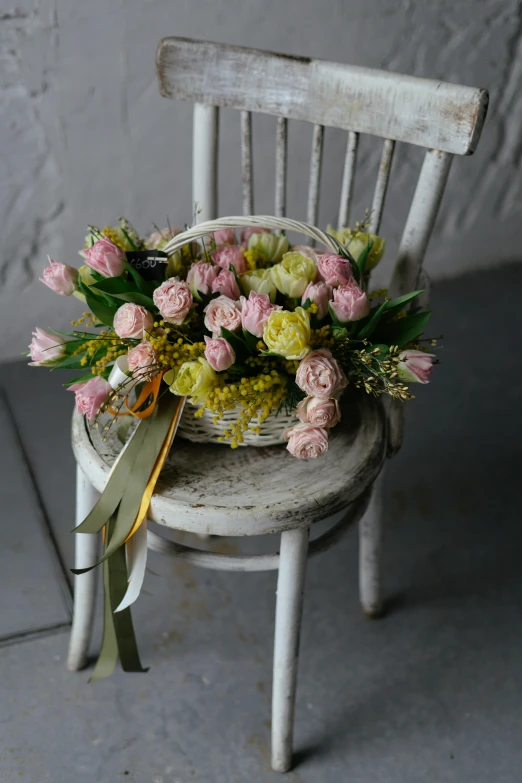 a chair with a bunch of flowers on it, inspired by Pierre-Joseph Redouté, romanticism, with an easter basket, pink yellow flowers, beautiful aged and rustic finish, sitting down