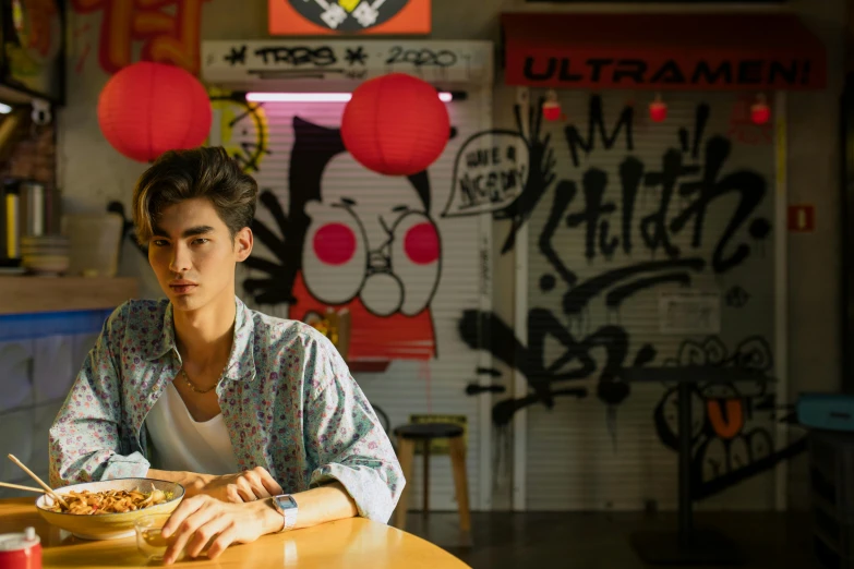 a man sitting at a table with a bowl of food, a portrait, inspired by Liam Wong, trending on pexels, graffiti, still from riverdale, japanese live-action movie, go nagai, press shot