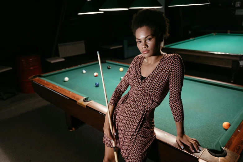 a woman standing next to a pool table, a portrait, by Bertram Brooker, pexels contest winner, patterned clothing, black young woman, sleek robes, promotional image