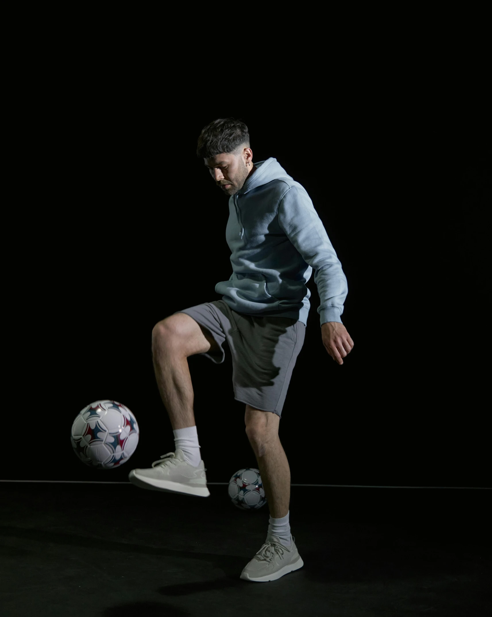 a man kicking a soccer ball in a dark room, wearing shorts and t shirt, profile image