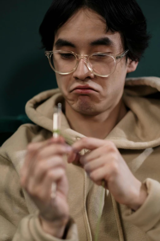 a close up of a person holding a cell phone, an album cover, inspired by Zhu Da, trending on pexels, hyperrealism, harry potter smoking weed, sad exasperated expression, holding a paintbrush, thick glasses