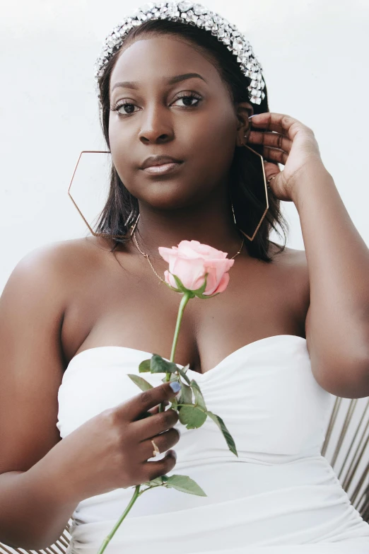 a woman in a white dress holding a rose, an album cover, by Dulah Marie Evans, trending on unsplash, brown skin. light makeup, headshot photoshoot, thicc, heart shaped face