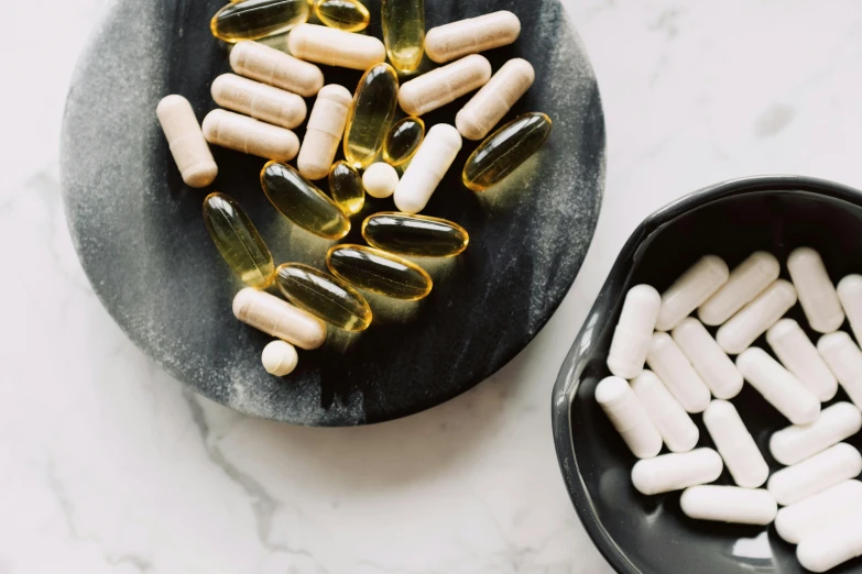 a plate of pills and a bowl of capsules, by Julia Pishtar, unsplash, smooth healthy skin, dark and white, made of glazed, a wooden