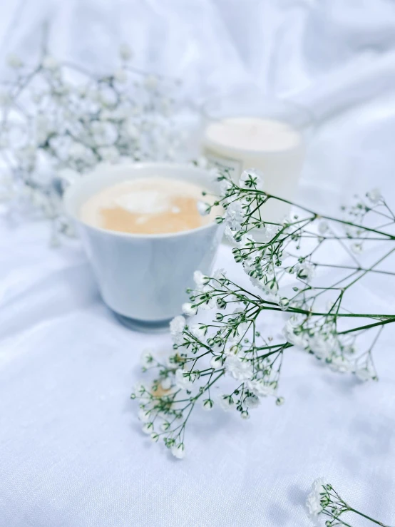 a cup of coffee and some baby's breath flowers, by Emma Andijewska, aestheticism, promo image, milky white skin, instagram photo, on a sumptuous tablecloth