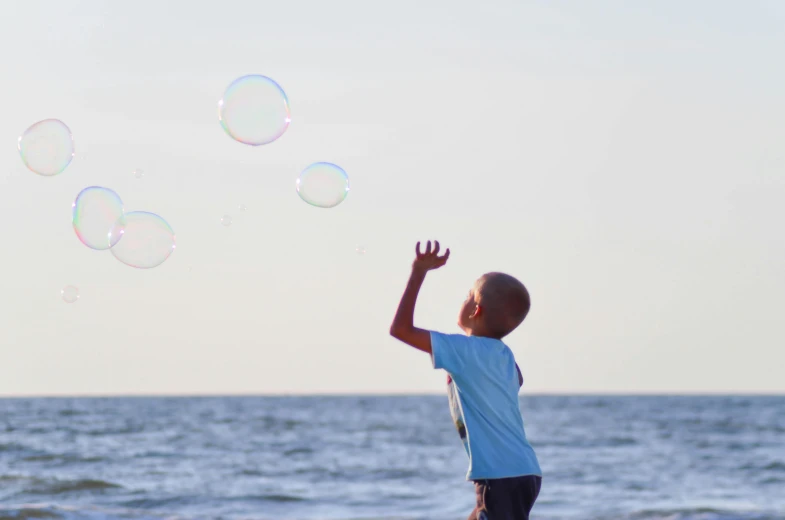 a young boy playing with soap bubbles on the beach, pexels contest winner, fan favorite, summer sky, instagram post, profile pic