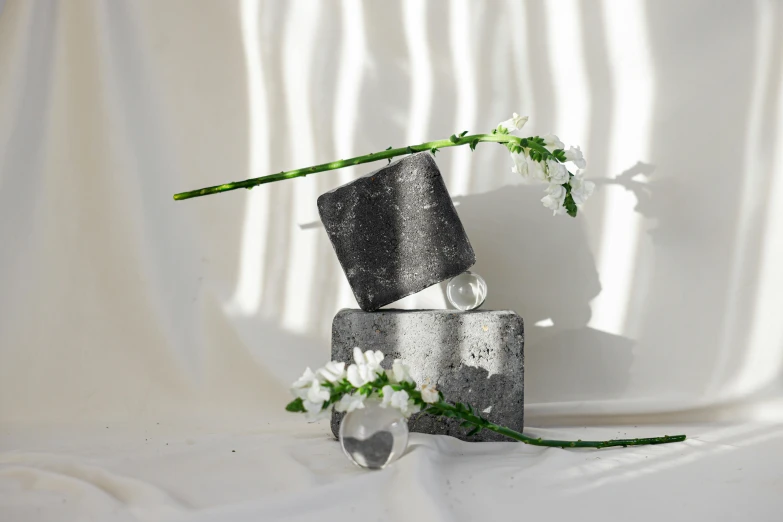 a vase that has some flowers in it, an abstract sculpture, inspired by Robert Mapplethorpe, unsplash, concrete art, cubes of ice around, black jewellery, levitating sand, sparkling atmosphere