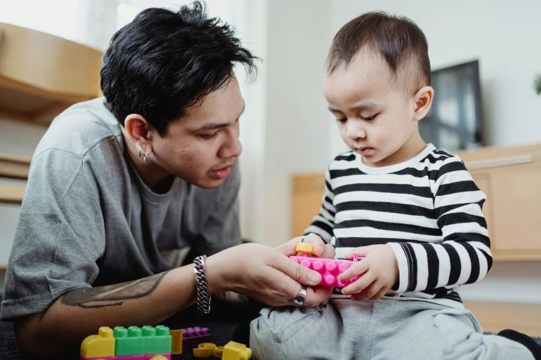 a man playing with a child on the floor, pexels contest winner, building blocks, te pae, portrait image, 1 4 9 3