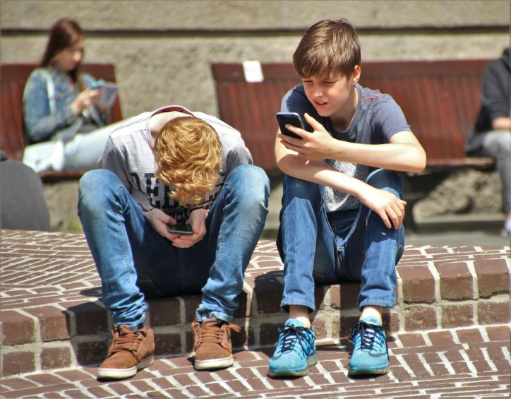 two boys sitting on brick steps looking at a cell phone, a photo, pexels, incoherents, in sunny weather, knees upturned, square, teenage no