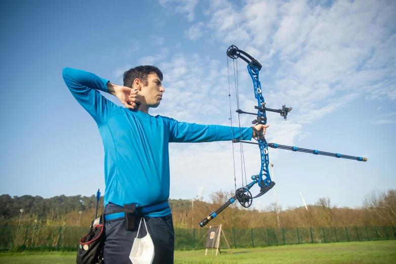 a man standing in a field holding a bow and arrow, pexels contest winner, sport clothing, avatar image, biomechanics, rectangle