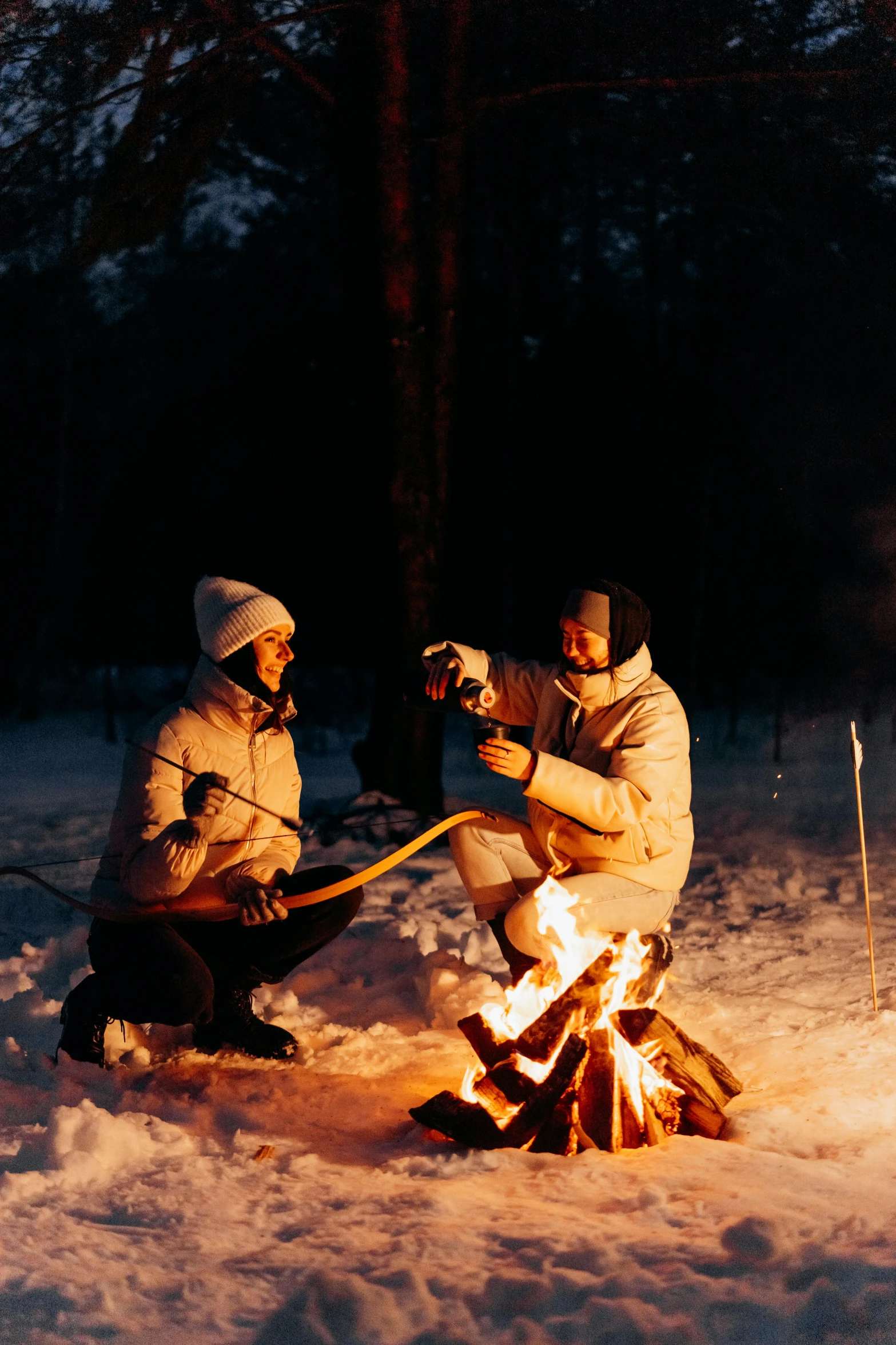 two people sitting around a campfire in the snow, inspired by Einar Hakonarson, drink, torch lighting, a wooden, tubing