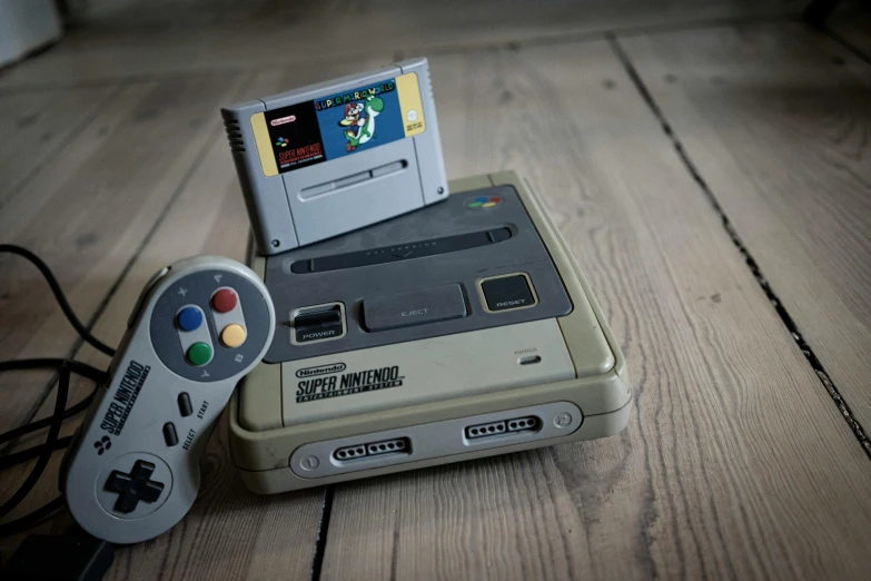 a nintendo game system sitting on top of a wooden table, snes, multicoloured, desaturated, liquid gold
