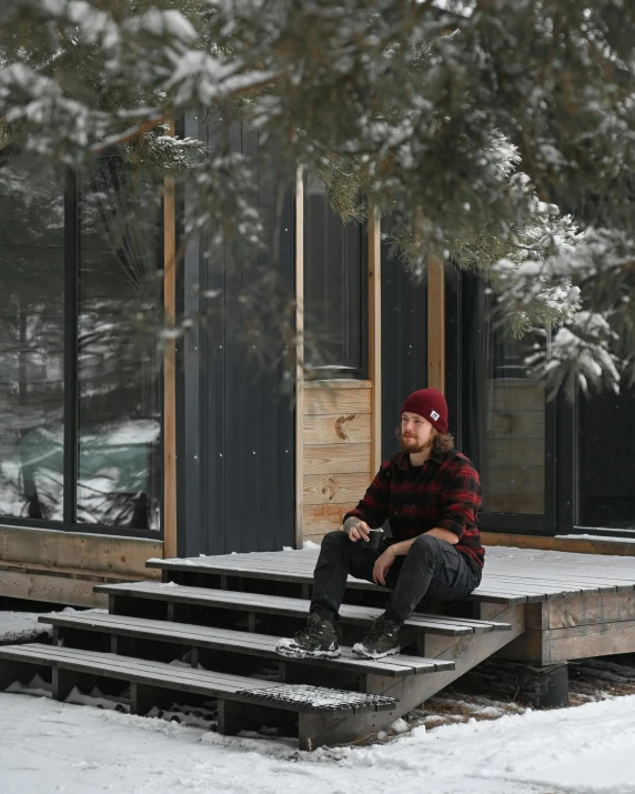 a man sitting on a porch in the snow, pexels contest winner, pine treehouse, lgbtq, very handsome, tiny house
