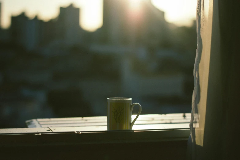 a coffee cup sitting on top of a window sill, sun behind her, tea, sits on a rooftop