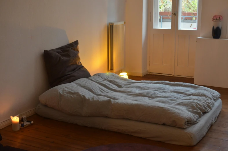 a bed sitting on top of a wooden floor next to a window, inspired by Sarah Lucas, light and space, moonlight grey, medium lighting, full body-n 9, handmade