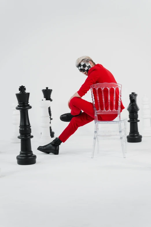 a man in a red suit sitting on a chair surrounded by chess pieces, an album cover, inspired by Horace Vernet, trending on pexels, portrait a woman like reol, zentai suit, justin bieber, aesthetic shot