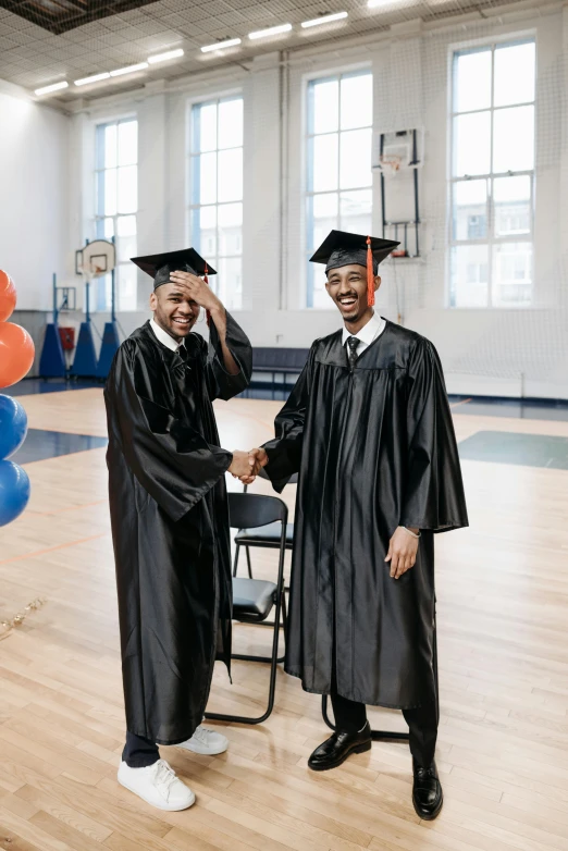 a couple of men standing next to each other on a wooden floor, academic art, wearing an academic gown, 2019 trending photo, sports photo, black man