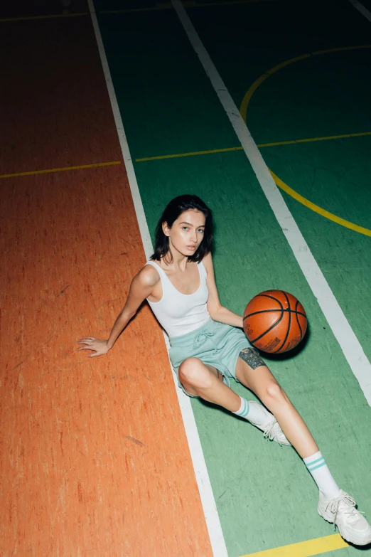 a woman sitting on a basketball court holding a basketball, inspired by Elsa Bleda, trending on dribble, kiko mizuhara, white shirt and green skirt, wearing a tank top and shorts, flat lay