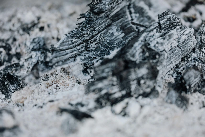 a pile of wood sitting on top of a pile of snow, a macro photograph, by Adam Marczyński, unsplash, abstract expressionism, coal dust, background image, limestone, chasm