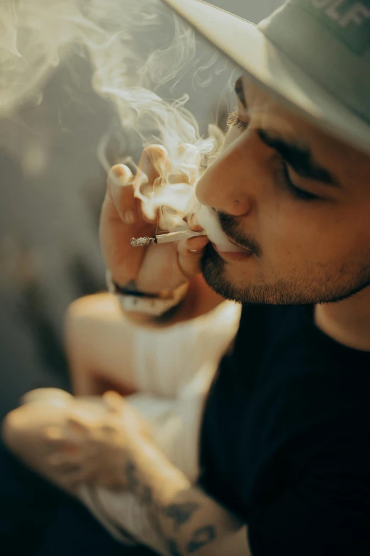 a man in a hat smokes a cigarette, trending on pexels, smoking a bowl of hash together, male with halo, enes dirig, hazy