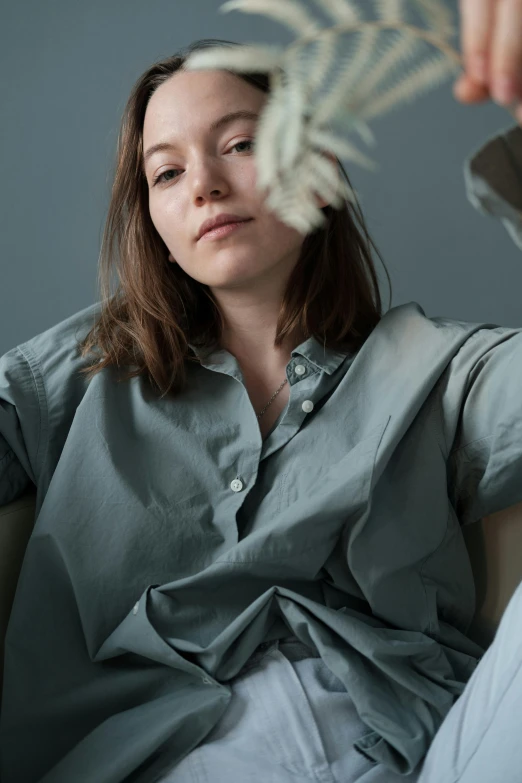 a woman sitting in a chair with a knife in her hand, a character portrait, by Grytė Pintukaitė, trending on unsplash, wearing a linen shirt, silver and muted colors, sitting on a bed, wearing polo shirt