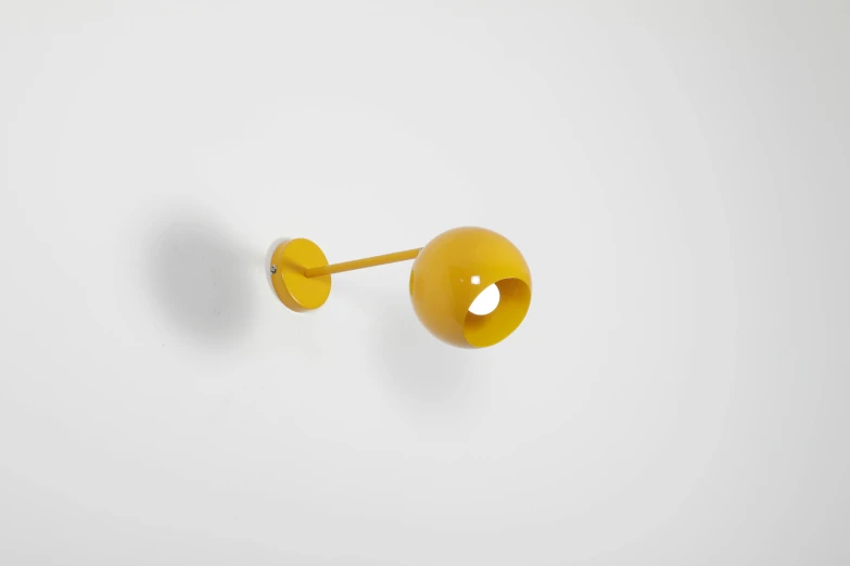 a close up of a yellow object on a white surface, inspired by Alexander Calder, sconces, ball, 150 mm, yellow orange