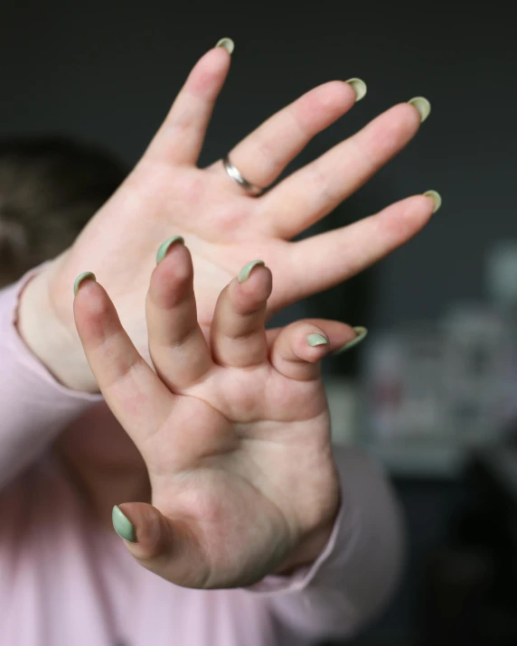 a woman making a stop sign with her hands, by Hannah Tompkins, happening, non-binary, unclipped fingernails, pale green glow, hand model