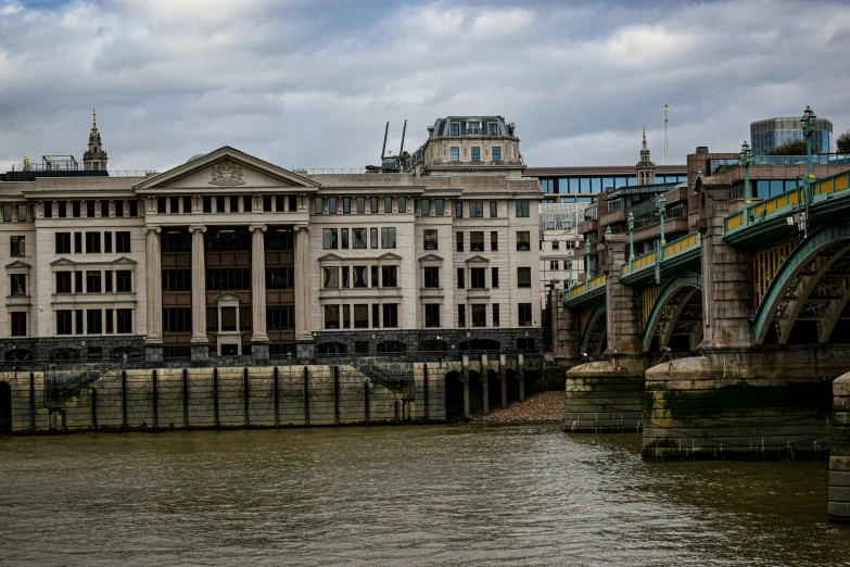 a bridge over a body of water with a building in the background, a photo, pexels contest winner, modernism, the thames is dry, on a great neoclassical square, brown, grey