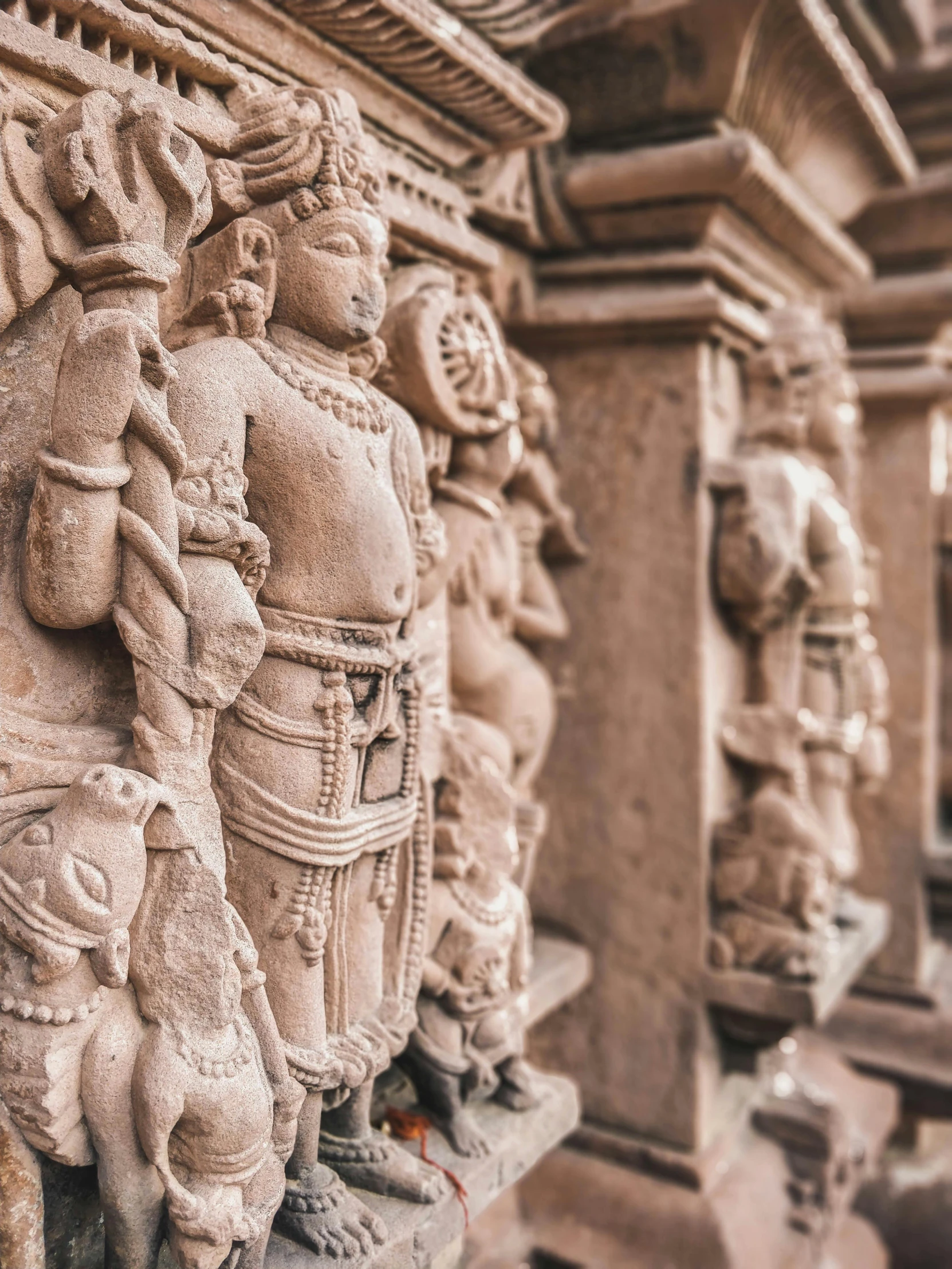 a close up of a statue on a wall, a marble sculpture, inspired by Thota Vaikuntham, pexels contest winner, elaborate carved wood balconies, red sandstone natural sculptures, pink marble building, detail shots