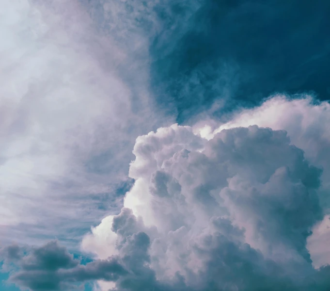 a plane flying through a cloudy blue sky, by Carey Morris, pexels contest winner, romanticism, towering cumulonimbus clouds, looking up onto the sky, major arcana sky, teal sky