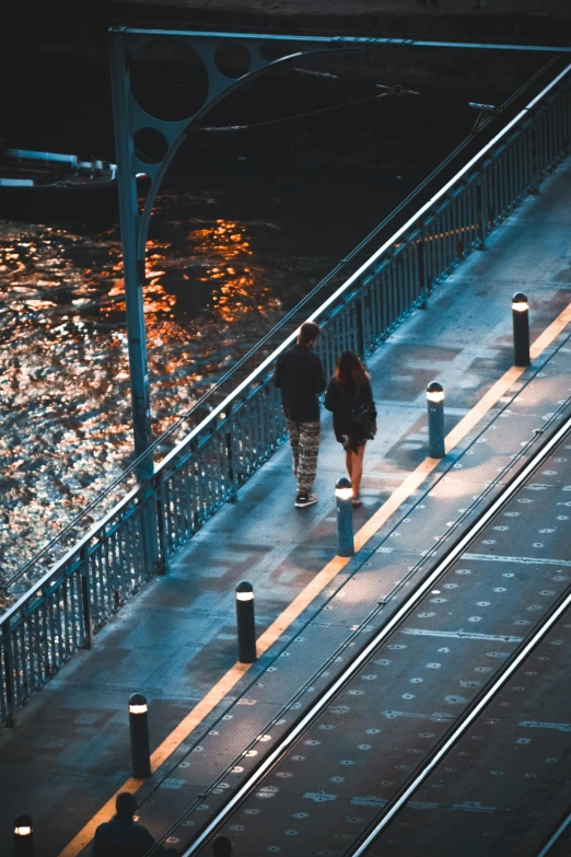 a couple of people standing on top of a train track, by Niko Henrichon, city street lights, beside a river, trending photo, walkway