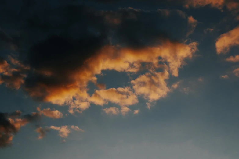 a large jetliner flying through a cloudy sky, an album cover, inspired by Elsa Bleda, unsplash, romanticism, orange clouds, ignant, black clouds, golden hour closeup photo