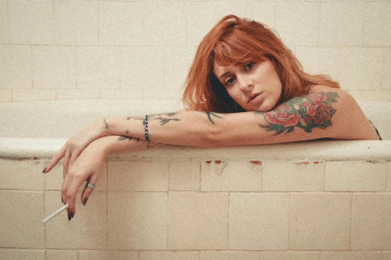 a woman sitting in a bathtub with a cigarette in her hand, a tattoo, inspired by Elsa Bleda, trending on pexels, bryce dallas howard, girl in a record store, solid background, crossed arms