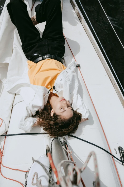 a man laying on top of a boat in the water, an album cover, trending on pexels, happening, photography of charline von heyl, woman in streetwear, timothee chalamet, sailing boat