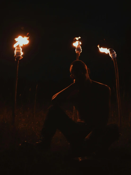 a man sitting in the middle of a field holding torches, pexels contest winner, realism, profile image, black metal aesthetics, tiny firespitter, profile picture
