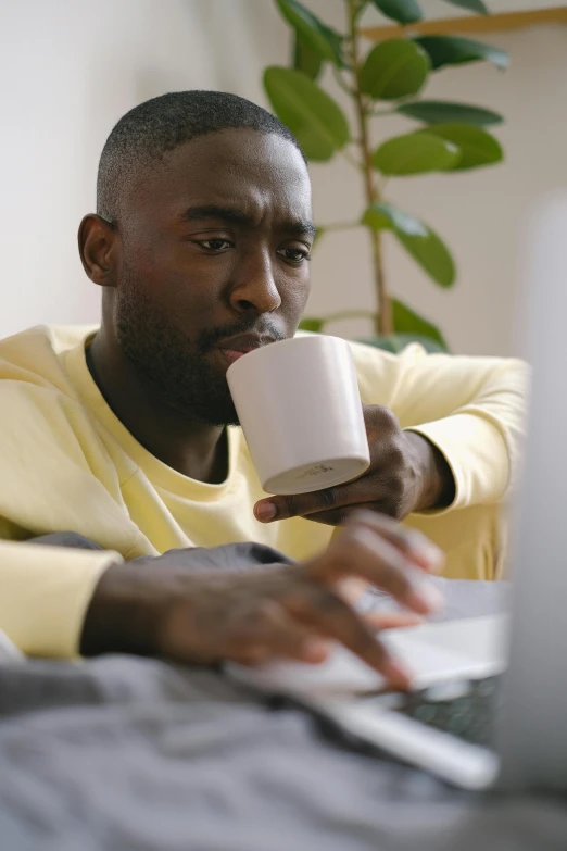 a man sitting on a couch using a laptop, trending on pexels, happening, mr robert is drinking fresh tea, jaylen brown, ignant, someone sits in bed