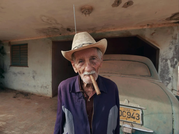 a man standing in front of a car with a cigar in his mouth, a portrait, by William Berra, pexels contest winner, photorealism, farmer, an elderly, juan miro, 15081959 21121991 01012000 4k