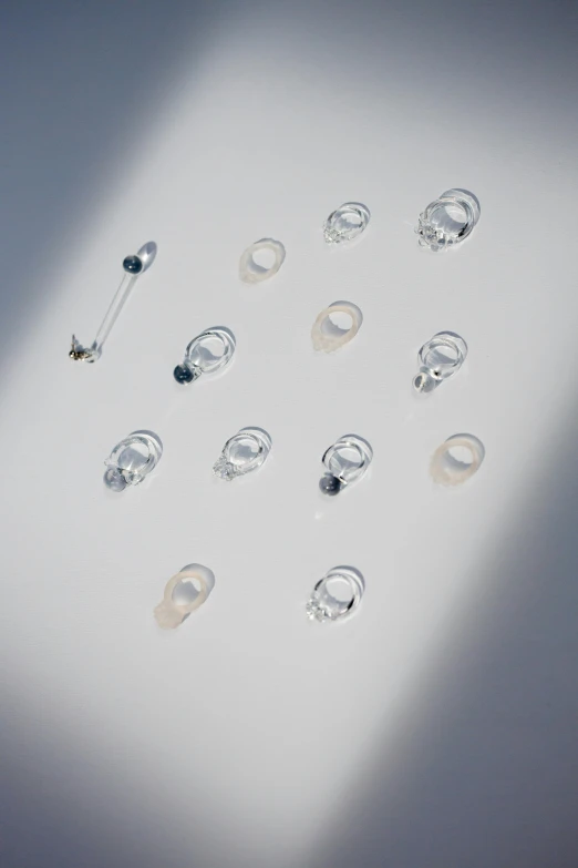 a bunch of rings sitting on top of a table, by Nina Hamnett, light and space, top down view, translucent crystals, silver earring, overview