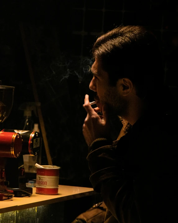 a man sitting at a table smoking a cigarette, a still life, inspired by Nan Goldin, pexels contest winner, ( ( theatrical ) ), absinthe, scene from live action movie, lgbtq