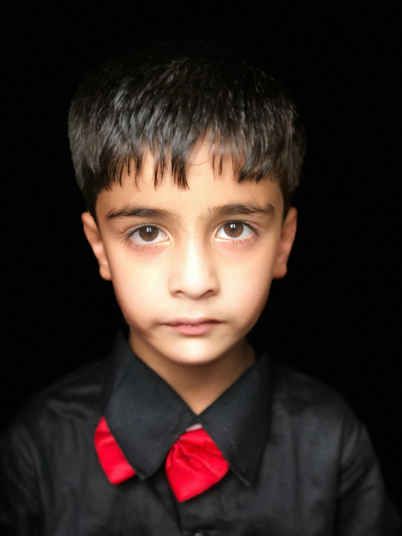 a young boy wearing a black shirt and a red bow tie, an album cover, pexels contest winner, hurufiyya, reza afshar, ((portrait)), eyes opened, taken in the late 2010s