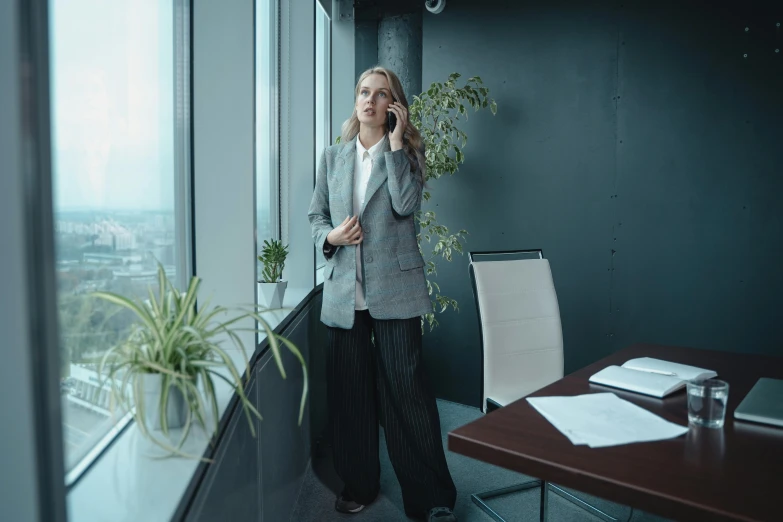 a woman talking on a cell phone in an office, by Emma Andijewska, cinematic realistic photo, wearing fashion suit, very tall, ad image