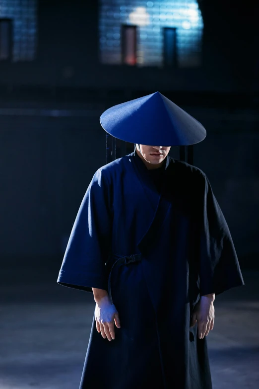 a woman wearing a blue hat standing in a dark room, inspired by Ma Quan, ninja outfit, wearing an academic gown, production photo, lee madgwick & liam wong
