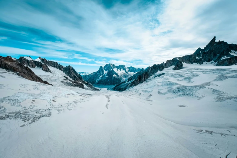 a person riding skis down a snow covered slope, an album cover, by Pierre Mion, pexels contest winner, epic land formations, 4 k cinematic panoramic view, northern france, glaciers and ice and snow